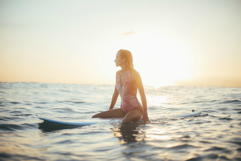 Woman sitting on a surfboard in the ocean waiting for a wave.